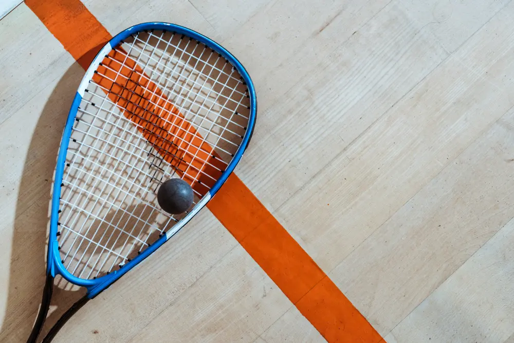 Close-up of squash racket and ball with player in background at Scamps Squash Club